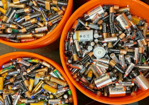 Brukte batterier sortert i oransje bøtter