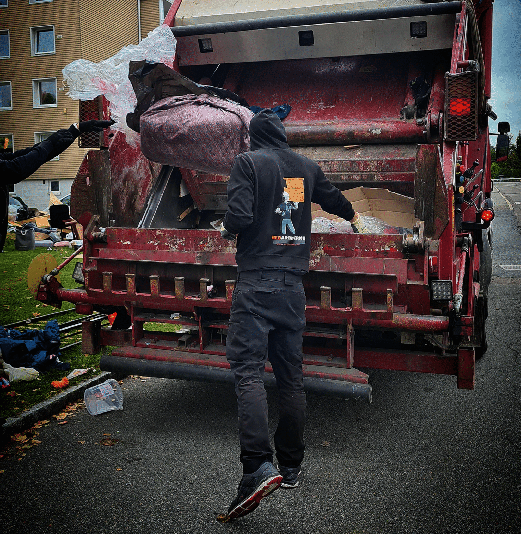 Medarbeider som kaster avfall i komprimatorbil